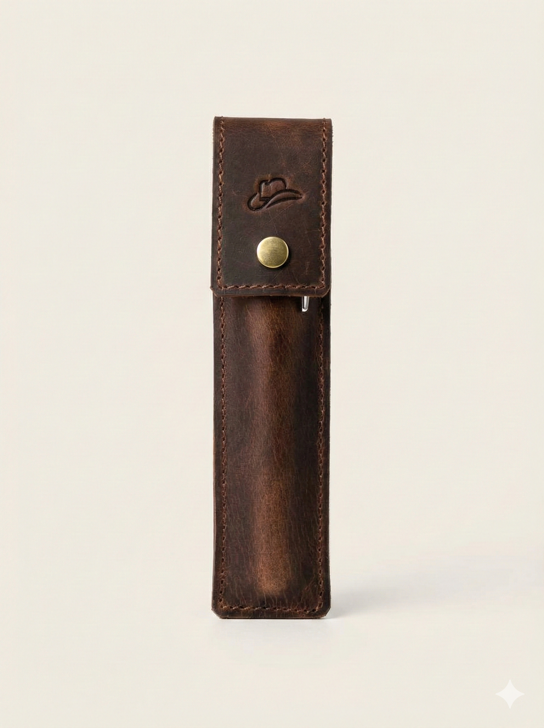 Brown leather pen holder with a gold button on a light beige background